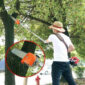 Une personne taille des branches avec une tronçonneuse télescopique.